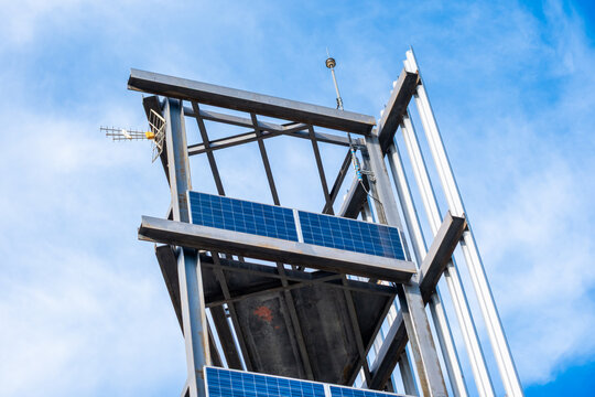 Steel structure with solar panels collecting solar energy. Communication antenna and lightning rod installed on a clear blue sky
