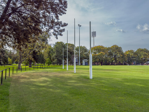 The iconic white AFL goal posts stand tall at Ikon Park (Princes Park) in Carlton, Melbourne, set against a backdrop of lush green turf on a bright, clear afternoon.