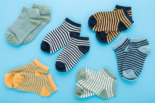 New colorful striped short socks for little child boy on light blue table background. Pastel color. Closeup. Clothes pattern. Top down view.