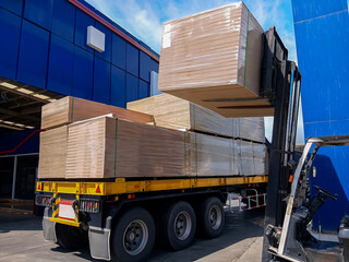 Forklift loading stacks of plywood, PB and HDF boards. Unloading from the truck for storage in the warehouse. Industrial logistics, construction materials supply chain, and wood distribution concept. © chaiwat