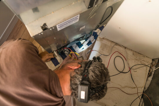 Close-up of a worker's hands using a digital multimeter
for the repair of a compressor refrigerator in a camper van