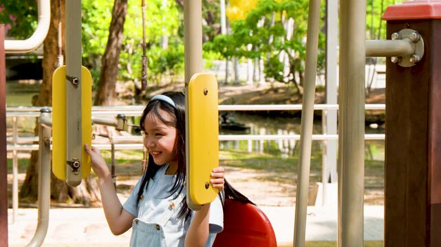 Happy Asian Child Using Outdoor Fitness Machine at a Sunny Public Park