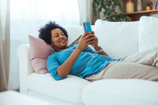 Relaxed Woman Enjoying Leisure Time Using Smartphone On Comfortable Sofa