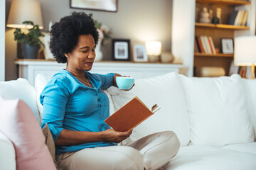 Woman Sipping Coffee and Reading a Book on Cozy Couch at Home
