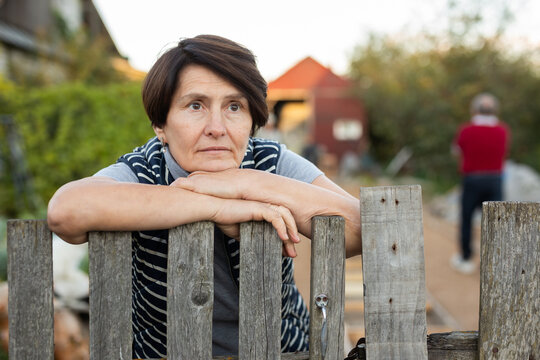Mature woman standing relaxed near fence in backyard smiling