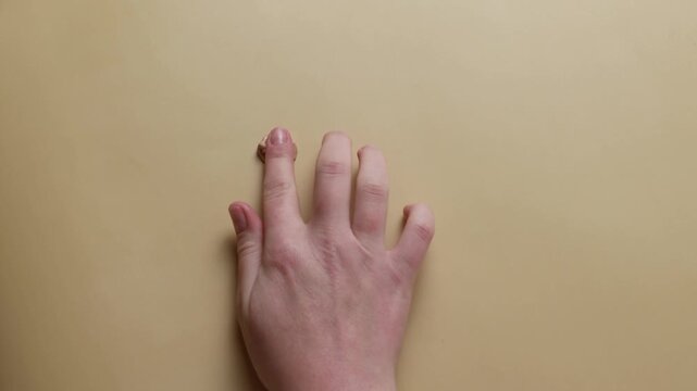 Woman applying liquid foundation on fingers, makeup routine with cosmetic concealer on beige background