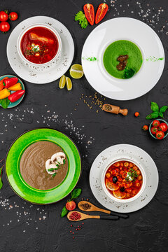 Assorted hot soups including borscht and vegetable cream soup. Four different soup bowls with red borscht green broccoli cream and brown mushroom soup.