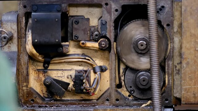 A detailed look inside the open casing of a mechanical device revealing metal gears, internal wiring, and electrical components.