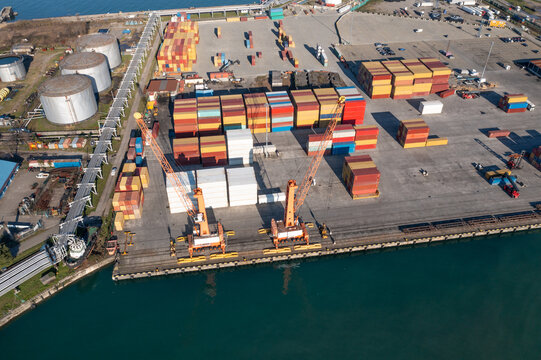 Global logistics container terminal, cargo cranes, stacked shipping containers, freight port infrastructure, import export supply chain, industrial harbor aerial view