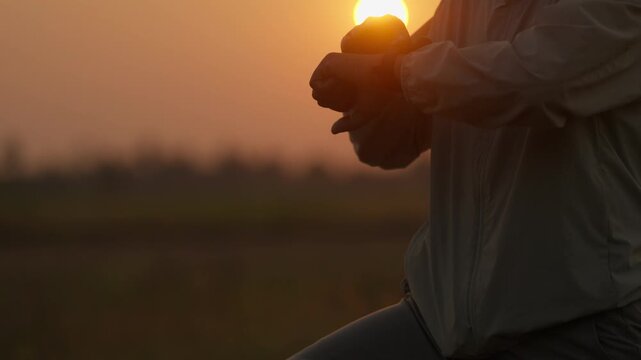Golden sun sets behind a runner. Dusk light glows softly behind moving figure. Runner strides across open field, motion blurred. Silhouetted form moves forward in quiet rhythm