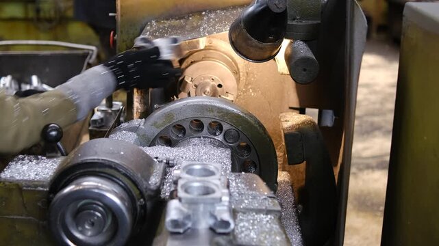 Detailed view of a rotating metal part being machined on a professional lathe with visible metal chips and motion blur.