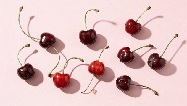 Fresh red and dark cherries on a light pink background with vibrant shadows