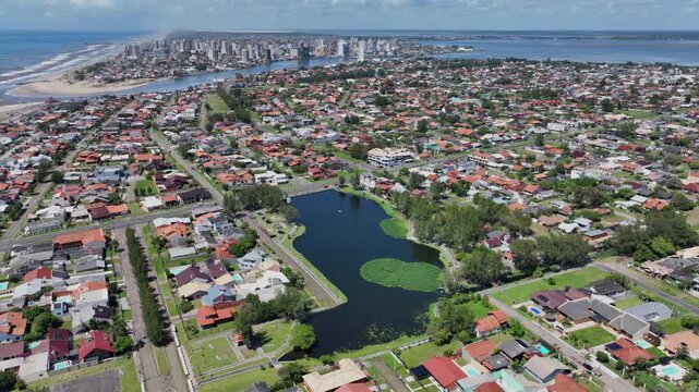 Partial aerial orbit over Lago do Braco Morto in Imbe, revealing the coastal neighborhood, beach, Atlantic Ocean and distant Tramandai skyline.