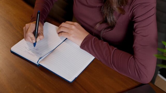 Top view woman writting, closing and reopening notebook on wooden desk