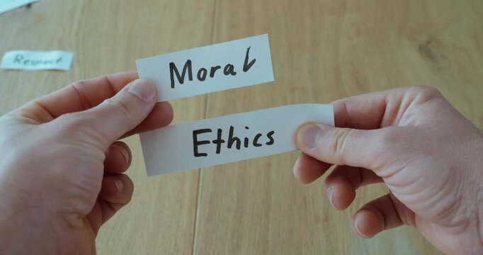 Hands holding papers labeled &ldquo;Ethics&rdquo; and &ldquo;Moral,&rdquo; representing values, principles, and human behavior.
