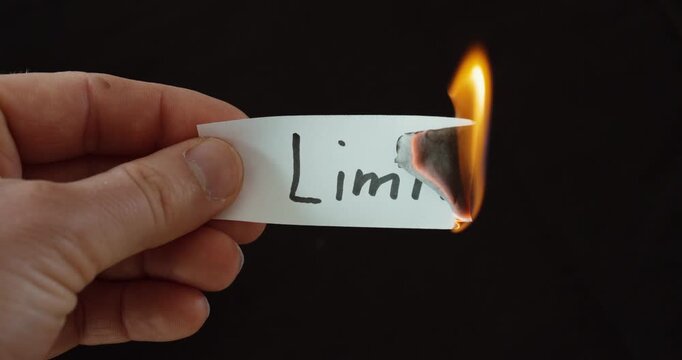 Hand burning a paper labeled &ldquo;Limits,&rdquo; symbolizing overcoming barriers, personal growth, and freedom.