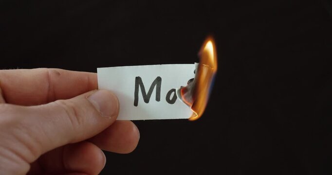 Hand burning a paper labeled &ldquo;Moral,&rdquo; symbolizing loss of ethics, values decline, and inner conflict.
