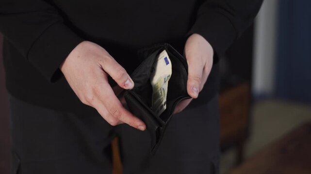 Close-up of hands opening an almost empty wallet with a few banknotes, showing money shortage, financial struggle, and poverty concept.