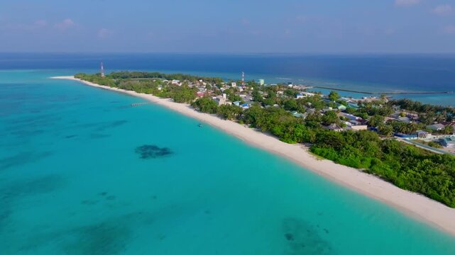 Beautiful aerial drone footage flying over the northern side of Vashafaru Island with a clear view across the island all the way to the southern coastline in northern Maldives.