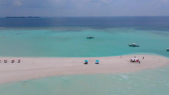 Cinematic aerial drone footage circling a beautiful tropical sandbank surrounded by crystal clear turquoise waters near Vashafaru Island in northern Maldives.