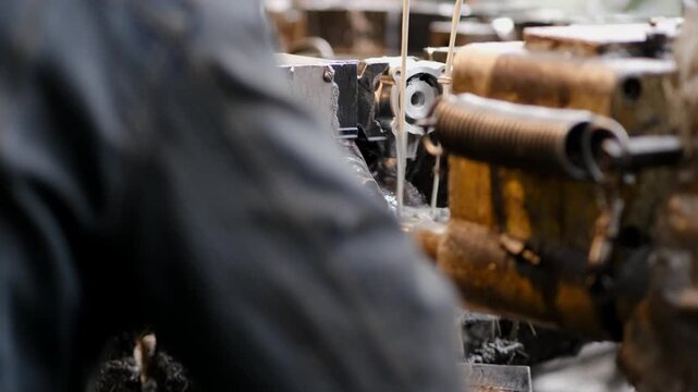 Close up shot of a metal part being processed on a machine with white industrial coolant fluid spraying for temperature control.