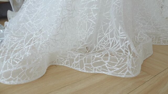 Close-up of the lace hem of a wedding dress. The bride's white dress. Wedding morning.