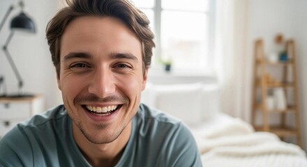 Fototapeta premium Portrait of a cheerful young man smiling at the camera in a bright home interior