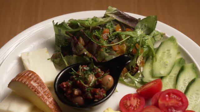 Delicious and healthy Turkish breakfast plate with assorted cheeses, scrambled eggs, and fresh vegetables, fa01