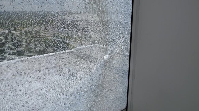 Close-up of the shattered tempered glass from a bullet or splinter shot. The glass is in small cracks. A broken window.