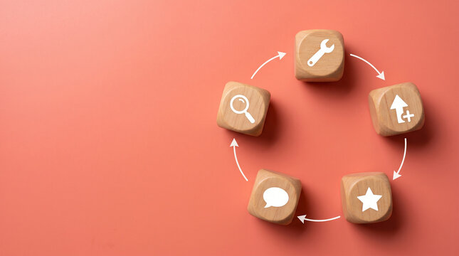 Five wooden cubes arranged in a circular loop with feedback, improve, and measure icons on a clean coral-pink matte background.