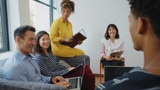 Multiethnic group of professionals attentively listening to a speaker during a collaborative meeting in a modern office, fostering teamwork, communication, and innovative business strategies