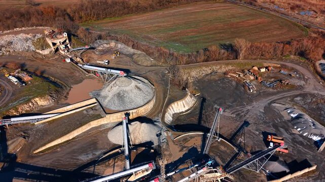 Construction site with tools. Heavy machinery works at a construction site near a field. Trucks move materials and equipment on the ground.