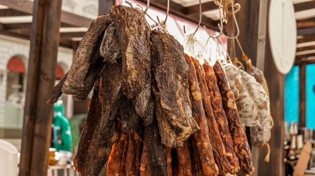 Assortment of cured meats hanging at an outdoor market stall