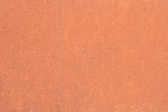 The texture of oriented strand board (OSB) with a terracotta (brick) colored surface.