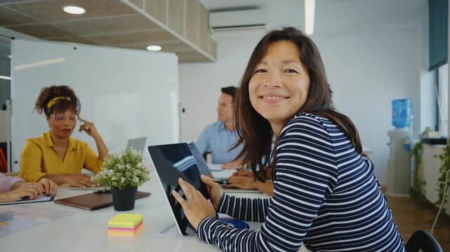 Multicultural business people brainstorming and talking about a new project during a briefing, analyzing data and charts on papers and laptops in a bright and modern conference room