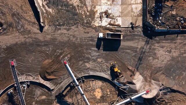 Vertical top view of conveyor belts at stone processing site. Nadir aerial shot of industrial machinery and aggregate stockpiles on the ground