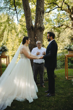 Outdoor wedding ceremony with a couple exchanging vows under a large tree