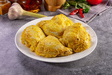 Raw chicken thighs in yellow turmeric marinade ready for cooking with spices © Andrei Starostin