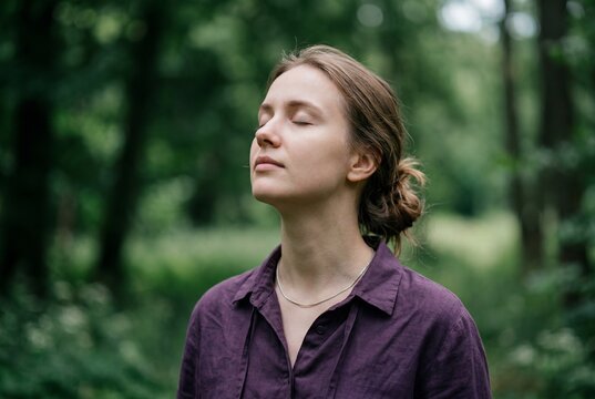 Young woman standing outdoors with her eyes closed taking a deep breath