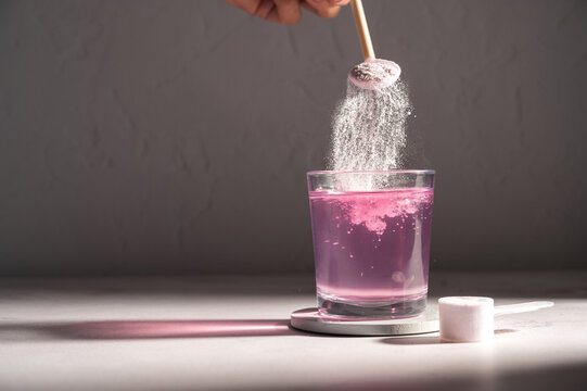 Pouring food supplement powder in glass of water. Collagen, protein powder, vitamins.
