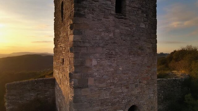 ancient stone tower at sunset with mountain landscape