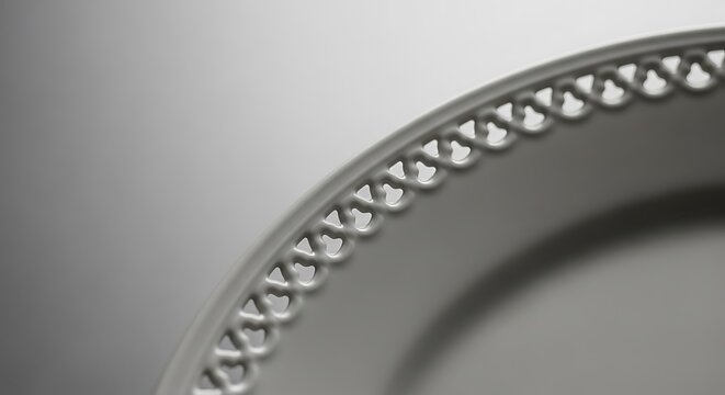 Close-up of elegant white ceramic plate with intricate lace pattern rim