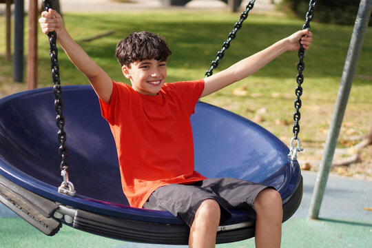 Holidays, summer and fun, healthy leisure and free time with the family. Preteen boy enjoying a nest swing in a park.