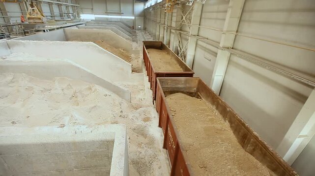 Unloading and storage of bulk materials in a indoors industrial warehouse. Unloading of railway open wagons and storage of bulk materials in a warehouse.