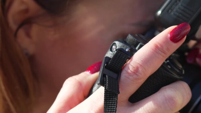 Photographer camera equipment woman with red nails holding professional camera while taking photos during outdoor shoot