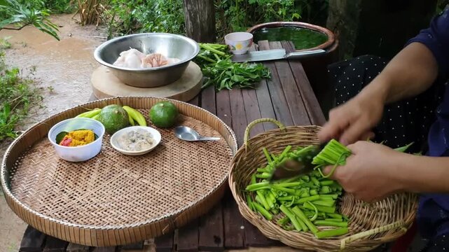 Slow motion close-up of hands preparing fresh green vegetables for cooking in rustic outdoor kitchen