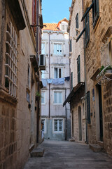 Fototapeta premium Narrow European street with weathered walls and laundry