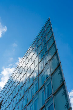 Looking upward in urban skyline as clouds reflection slides over glass windows on modern facade building architecture emphasizing height and aspiration