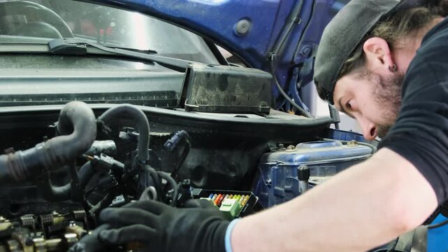 Auto repair technician inspects coolant hose during repair. Man touches mechanism with hands assessing condition of special system