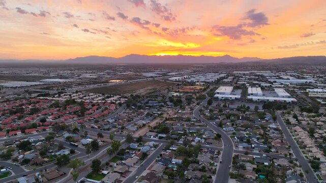 Aerial view of a sprawling residential area bathed in the warm hues of sunset, with mountains on the horizon, Chandler, Arizona, United States.